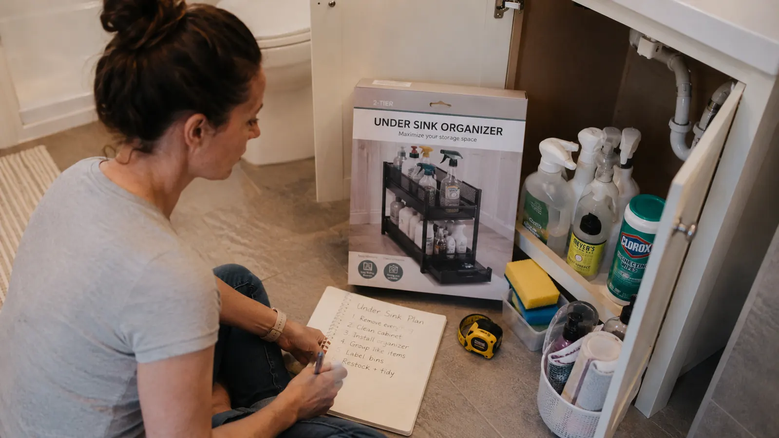 Open bathroom cabinet showing a clean, organized under-sink space with tiered storage in a rental apartment